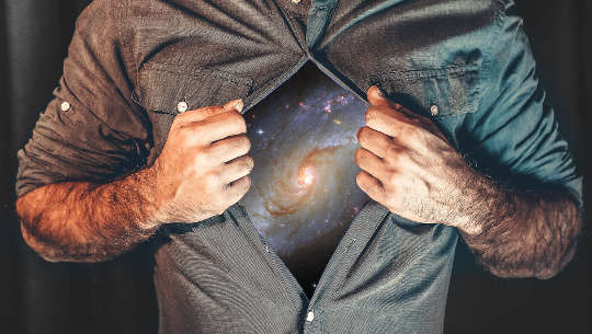 man holding open his shirt to show the galaxy and universe (like a Superman symbol)