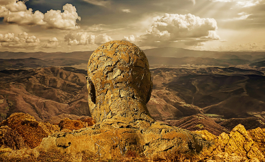 image of the statue of a man made of stones, overlooking a valley
