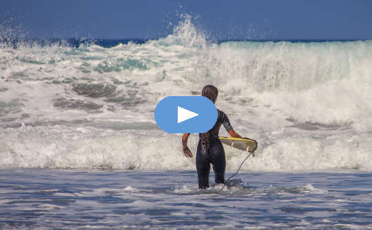 surfer with tiny surfboard facing huge waves