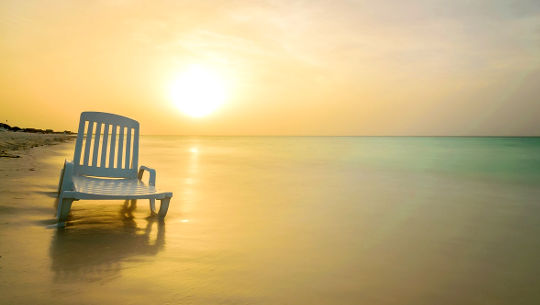 A chair partially in the water on a sandy beach