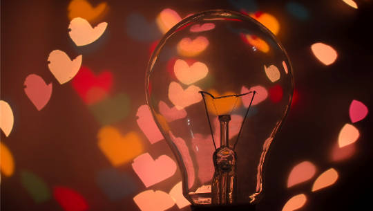 a lightbulb surrounded by heart symbols