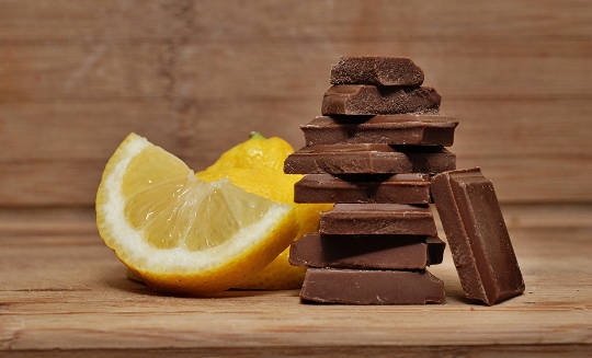 A wedge of a lemon and a stack of chocolate pieces
