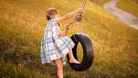 young girl climing on to a tire swing