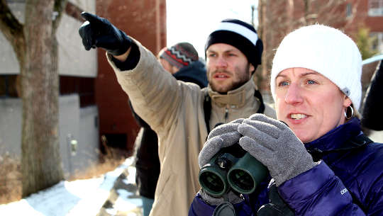 woman holding binoculars while the man next to her points at the horizon
