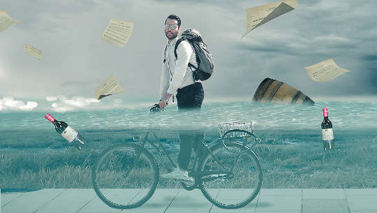 man riding a bicycle through waist high flood water