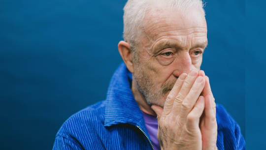 man reflecting with his hands in prayer pose held over his mouth