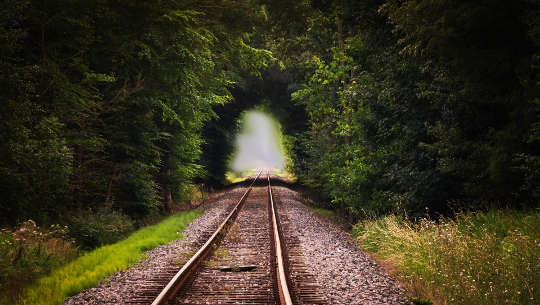 railroad track leading in to a bright tunnel