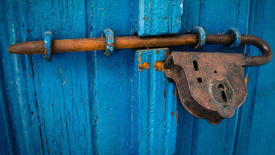 an ancient padlock on a blue door