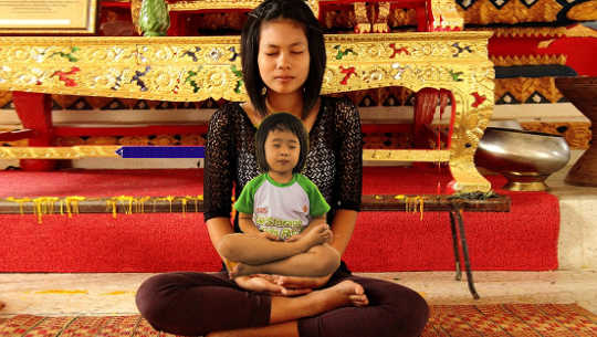 a woman in lotus position with a child, perhaps her inner child, on her lap also in lotus position