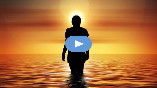 woman standing in the ocean looking at the rising sun