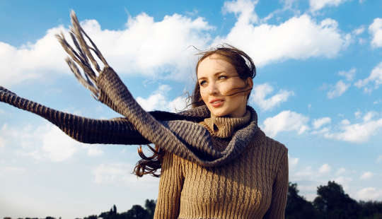girl standing outside with her scarf blowing in the wind