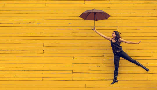 a woman dancing holding an umbrella up high