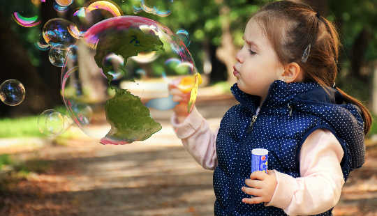 young girl blowing a huge soap bubble