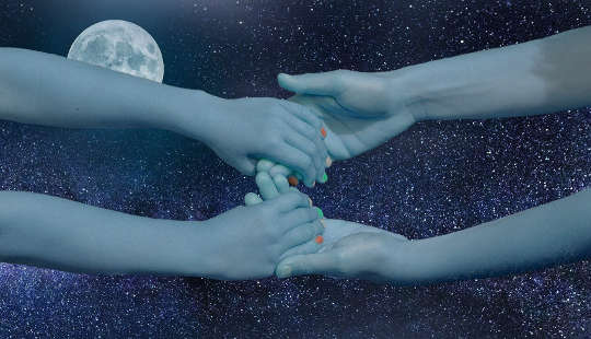 two peoples hands reaching and joining across the sky and a full moon