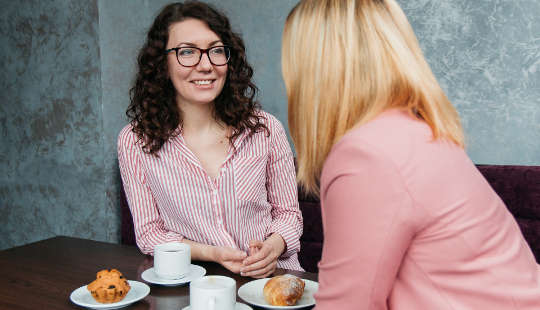 two women talking over coffee and muffins